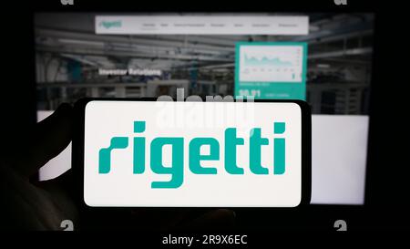 Person holding smartphone with logo of US company Rigetti Computing Inc. on screen in front of website. Focus on phone display. Stock Photo