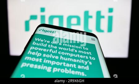 Mobile phone with webpage of US company Rigetti Computing Inc. on screen in front of business logo. Focus on top-left of phone display. Stock Photo