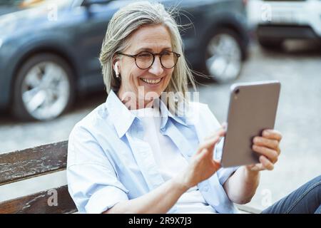 Integration of technology and daily lives of older individuals, and their ability to stay connected and engage in digital communication. Happy senior lady enjoying online conversation on tablet PC. High quality photo Stock Photo