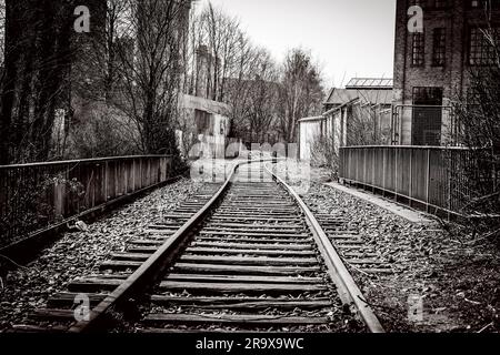 Railroad tracks going through an abandoned city with old buildings Stock Photo