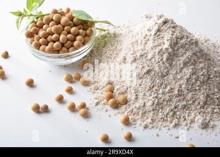 Detail of whole and refined soybean flour on white kitchen bench with glass bowls filled with grains and flour. Top view. Stock Photo