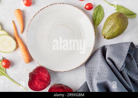 White plate in the center among vegetables and fruits. Vegan food, Low-carb, plant-based diet, copy space. Stock Photo