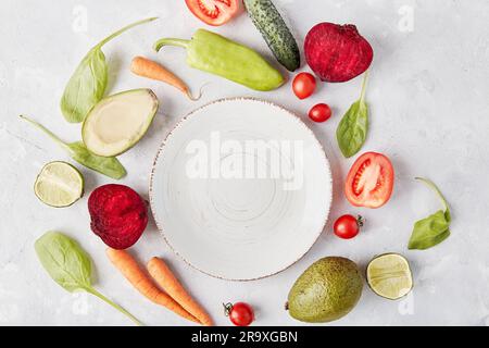 White plate in the center among vegetables and fruits. Keto, FODMAP, Paleo, Low-carb, plant-based diet concept. Stock Photo