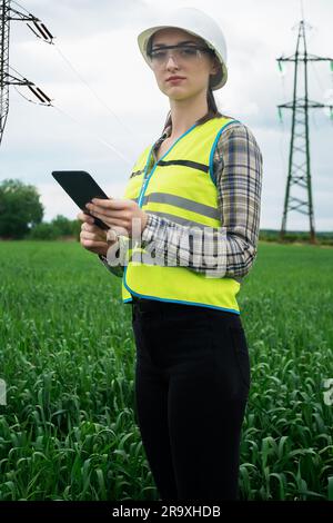 electrical engineer woman high voltage power industry, electrician worker working, energy concept, high voltage electrical tower, power line, working Stock Photo