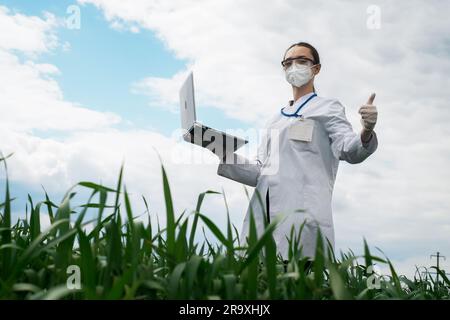 Agronomist using tablet and technology in agricultural corn field. The farmer walks through the field with a tablet. Biologist woman with laptop Stock Photo