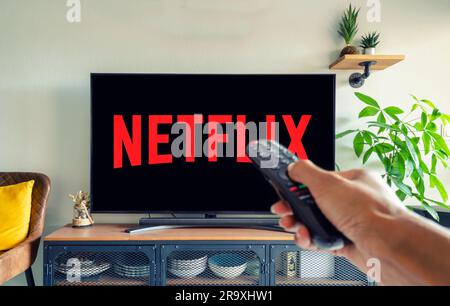 Hand of a black woman holding a remote control and watching Netflix. Stock Photo