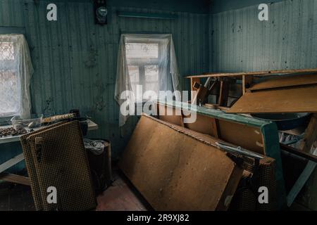 The room of an abandoned old village house with a pile of old broken furniture and other rubbish Stock Photo