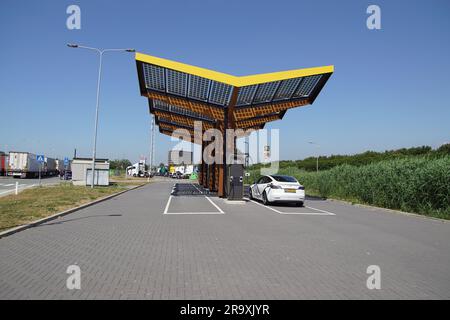 Fastned charging station, charge point with electric car on rest area Peulwijk, a car park along the A4. Solar panels on the roof. Netherlands, June Stock Photo