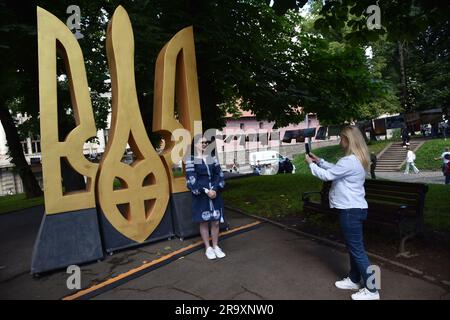 Lviv, Ukraine. 28th June, 2023. A woman is photographed against the background of the big Trident (the coat of arms of Ukraine) during the celebration of the Constitution Day of Ukraine. Ukraine celebrated the 27th anniversary of the adoption of the country's basic law - the constitution. In the conditions of the Russian-Ukrainian war, official events were very short. In Lviv, the Ukrainian flag was raised, honor guard marched, and a military band performed. Credit: SOPA Images Limited/Alamy Live News Stock Photo