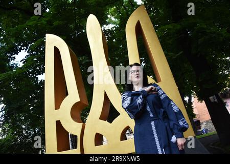 Lviv, Ukraine. 28th June, 2023. A woman is photographed against the background of the big Trident (the coat of arms of Ukraine) during the celebration of the Constitution Day of Ukraine. Ukraine celebrated the 27th anniversary of the adoption of the country's basic law - the constitution. In the conditions of the Russian-Ukrainian war, official events were very short. In Lviv, the Ukrainian flag was raised, honor guard marched, and a military band performed. Credit: SOPA Images Limited/Alamy Live News Stock Photo