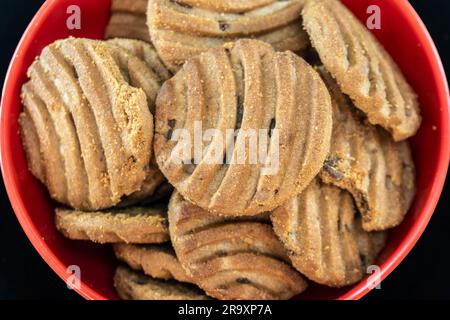 Very Close-Up And Top View Of Chocolate Chip Cookies Or Biscuits On Red Bowl. Isolated On Magenta Background. Selective Focus Stock Photo