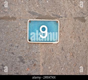 9, nine - light blue plate on gray stone surface. Stock Photo