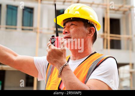 Engineer worker with safety hard hat using walkie-talkie working at construction site outdoor, Construction worker checking and controlling project Stock Photo
