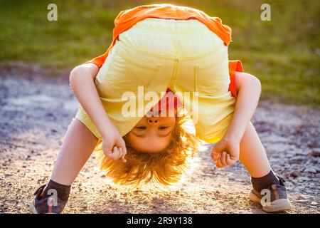 Happy cute child standing upside down. Playing fools kid. Young man happy positive smile playful fooling dance. Cute boy having fun. Child playing Stock Photo