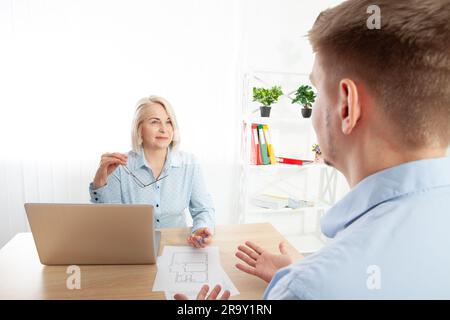 Headshot of a smiling professional financial advisor talking to a client in the office. Pleasant real estate agent making a good deal offer to a man Stock Photo