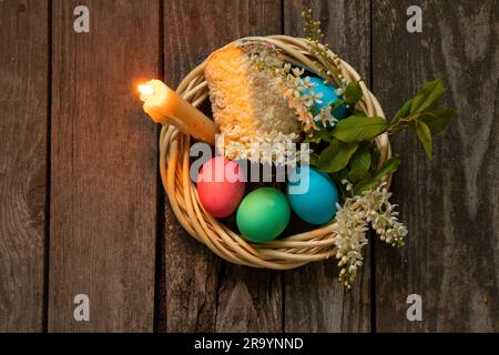 Easter dinner, colored chicken eggs and candle flame on an old wooden table in the evening Stock Photo