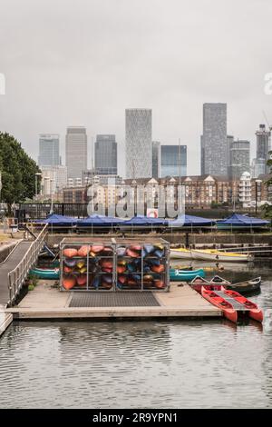 Colourful canoes and boats on Shadwell Basin with the skyscrapers of Docklands and Canary Wharf in the background, London, England, U.K. Stock Photo