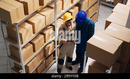 Multiethnic group of employees working on inventory, planning stock logistics for delivery and transportation. Team of people checking products on tablet and papers, industrial business. Stock Photo