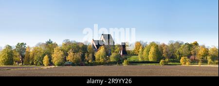 Agricultural land and trees with old Uppsala church against clear blue sky in the background Stock Photo