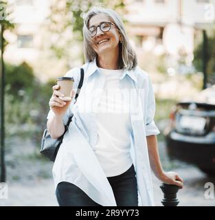 Woman in good mood, radiating happiness and contentment with life. The image features lady standing on a street, exuding joyful and carefree demeanor. . High quality photo Stock Photo