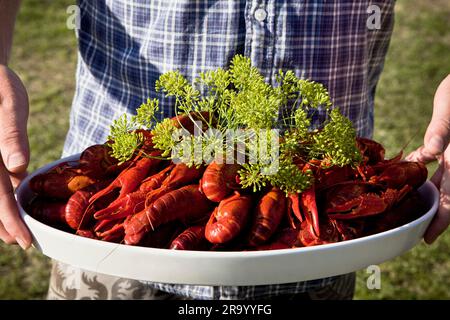 Close-up midsection of a person holding a big plate of crayfish Stock Photo