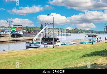 Sambeek, Netherlands - July 9. 2023: Transport ship with gravel and sand cargo in dutch lock, car at crane Stock Photo