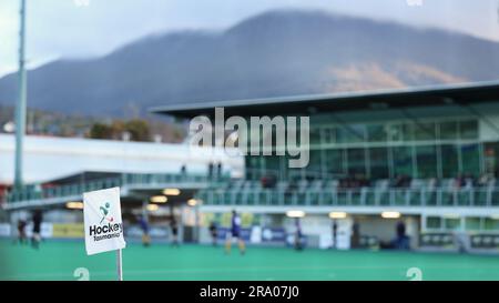 A flag on a pole with the Hockey Tasmania logo visible. Mt Wellington (Kunanyi) in the background with deliberately blurred stadium, players and adver Stock Photo