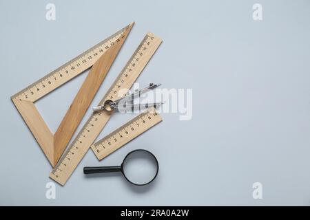 Different rulers, magnifying glass and compass on yellow background ...