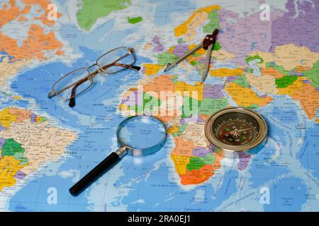 On a map of the world there is a magnifying glass, compass, compasses and glasses Stock Photo
