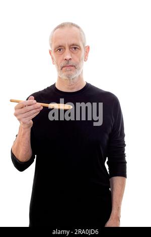 Adult man in black holds a spoon in each and looks serious Stock Photo