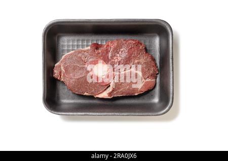 A slice of mutton leg in a black foam tray, isolated on white background Stock Photo