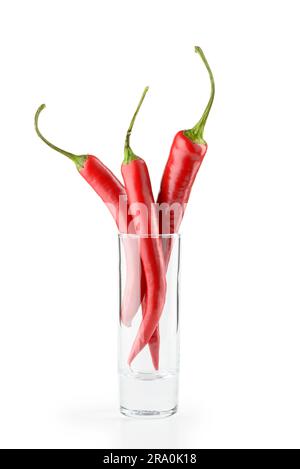 Three hot red chili peppers in a vodka glass, isolated on white background Stock Photo