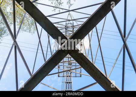 Detail of an electricity pylon against blue sky: high voltage electric cables seen from below Stock Photo