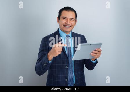 young businessman smiles at camera with raised finger and a tablet, real estate seller, one person Stock Photo