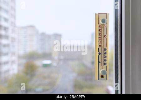 A thermometer, fixed out of the window, shows that it is zero degree celsius outdoor, while it is warm inside the room Stock Photo