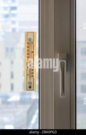 A thermometer, fixed out of the window, shows that it is zero degree celsius outdoor, while it is warm inside the room Stock Photo