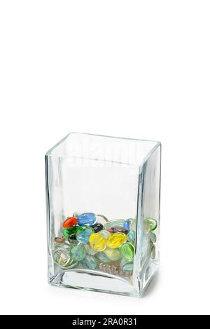 A Parallelepipedic transparent crystal vase isolated on white background, half full of colored glass beads Stock Photo