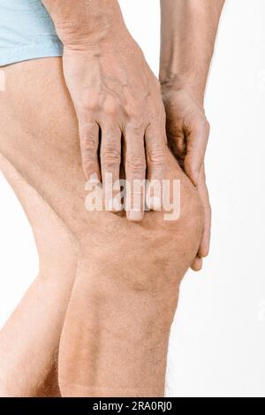 Athlete man massaging a painful quadriceps and the knee after a sport accident. It could be a quadriceps tendinopathy, a muscle elongation, a medial Stock Photo