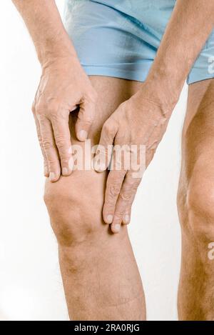 Athlete man massaging a painful quadriceps and the knee after a sport accident. It could be a quadriceps tendinopathy, a muscle elongation, a medial Stock Photo