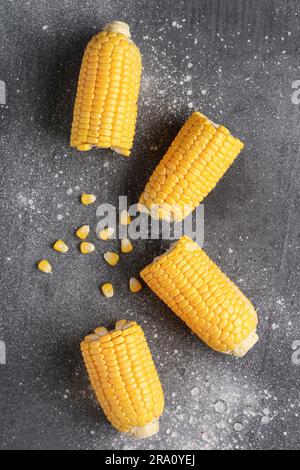 Cut fresh corn cobs and seeds on grey background Stock Photo