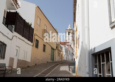 Cobbled streets and historic house fronts in Rua dos Ferreiros, with Igreja de Sao Sebastiao de Lagos in the background, in the old town of Lagos Stock Photo