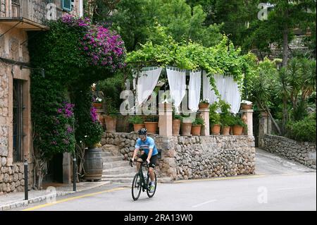 Racing cyclists in the artists' village of Deia on the edge of the Tramuntana mountains, Majorca, Spain Stock Photo
