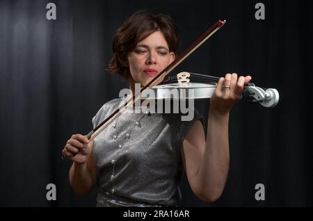 Half-length portrait of a woman playing the violin on a black background Stock Photo