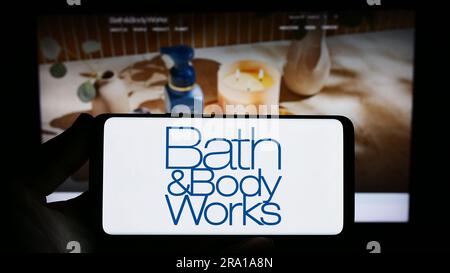 Person holding smartphone with logo of US retail company Bath and Body Works Inc. on screen in front of website. Focus on phone display. Stock Photo