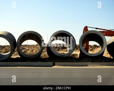 Cairo, Egypt, June 24 2023: A digging excavator for preparations of large water pipe parts in place, sanitation pipes, improvement of infrastructure a Stock Photo