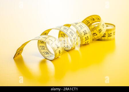 Yellow measuring tape on the yellow background. Stock Photo