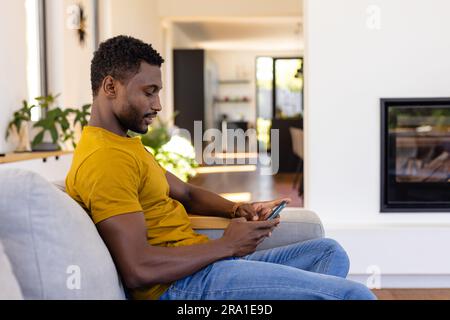 Happy african american man using smartphone in living room Stock Photo