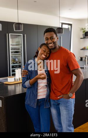 Portrait of happy african american couple embracing in kitchen Stock Photo