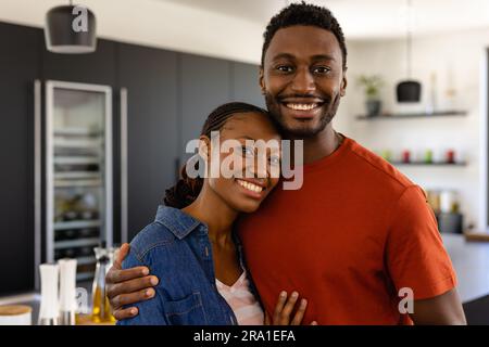 Portrait of happy african american couple embracing in kitchen Stock Photo