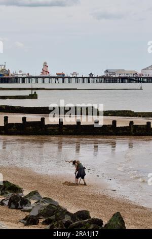 Metal detectorist searching the beach at Clacton on Sea, Stock Photo